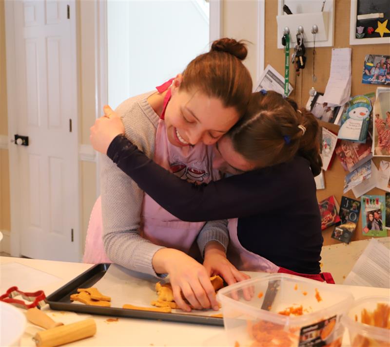 Two friends hugging while baking together in the kitchen